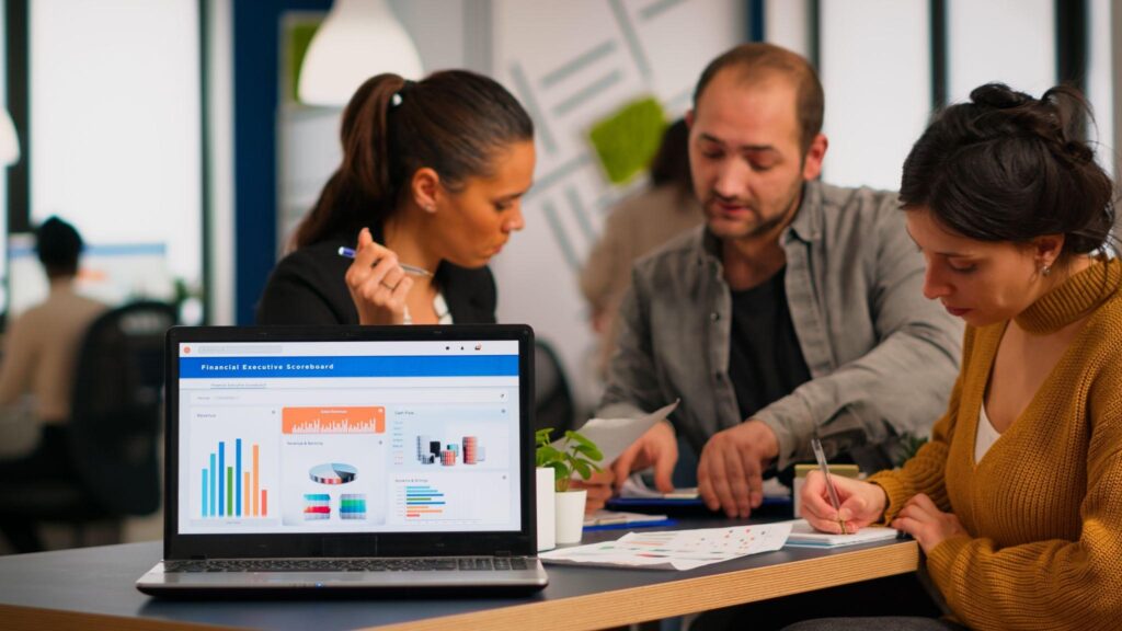 Team analyzing financial data on laptop.