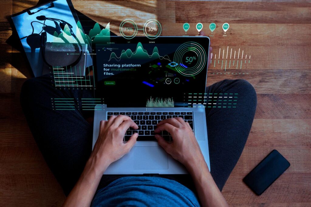 Person typing on laptop with data graphics overlay.