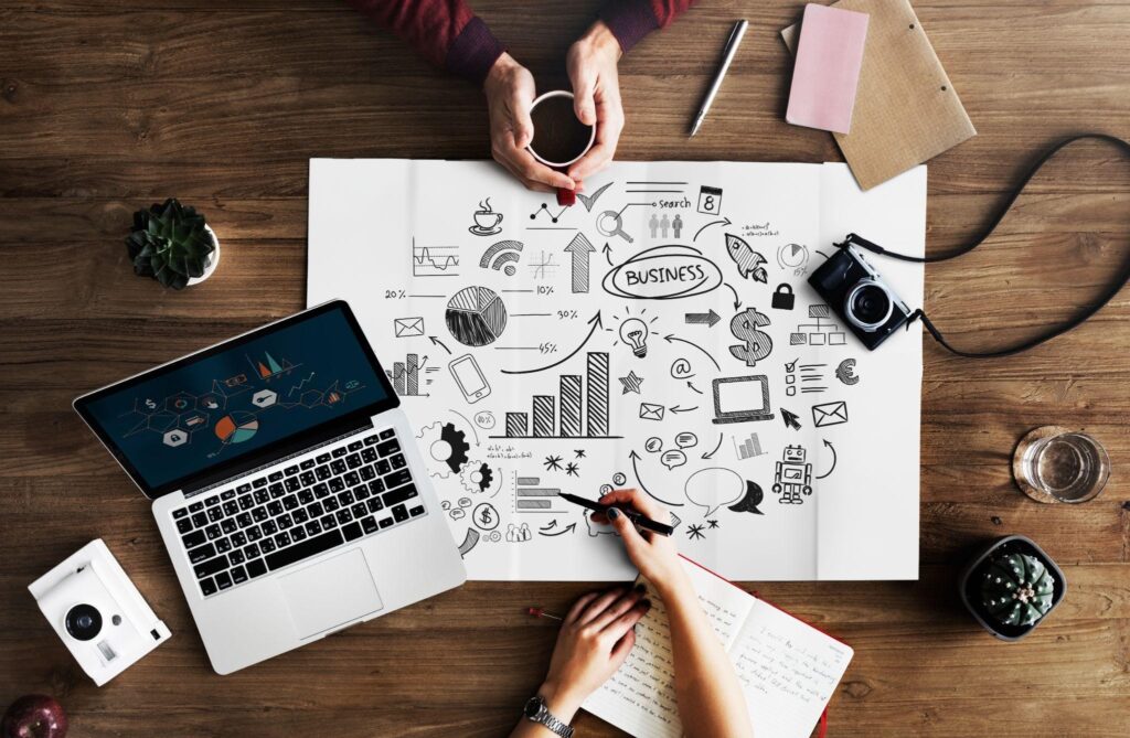 Desk with business strategy drawings, laptop, and notes.