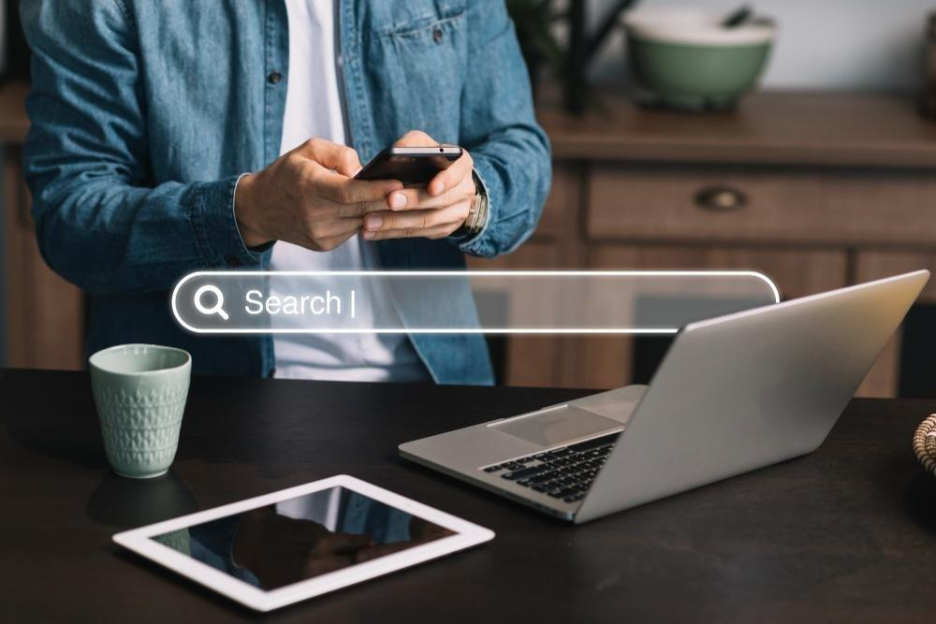 Person using smartphone at desk with laptop