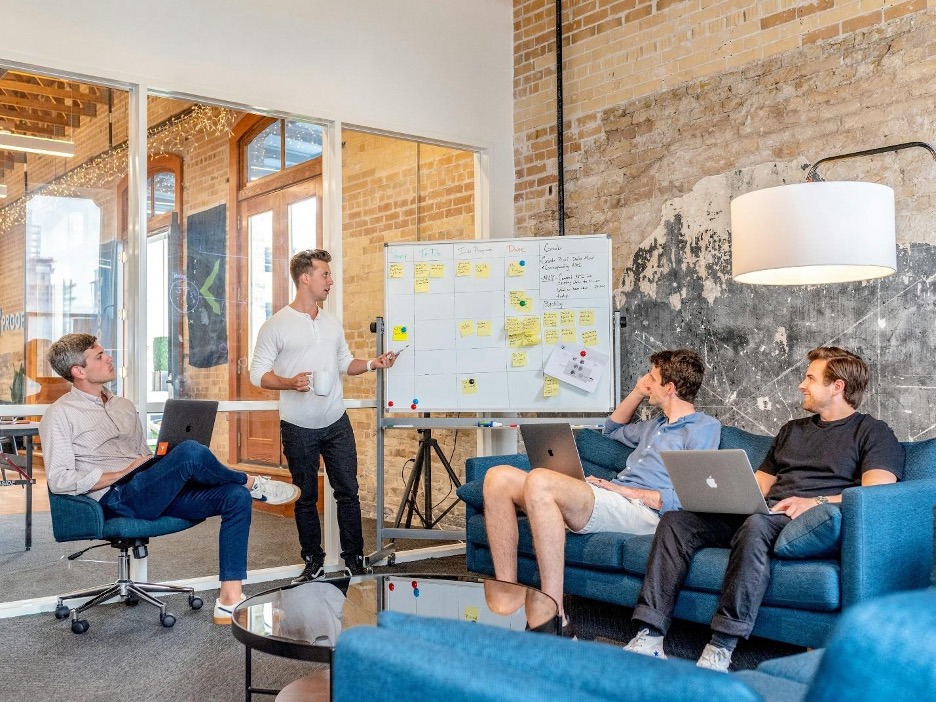 Team meeting with whiteboard discussion in office.